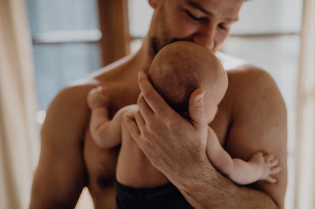 Un padre carga a un bebé y sus cuerpos se tocan