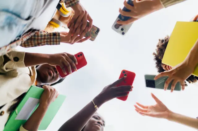 Des élèves partagent du contenu sur leurs smartphones après les cours