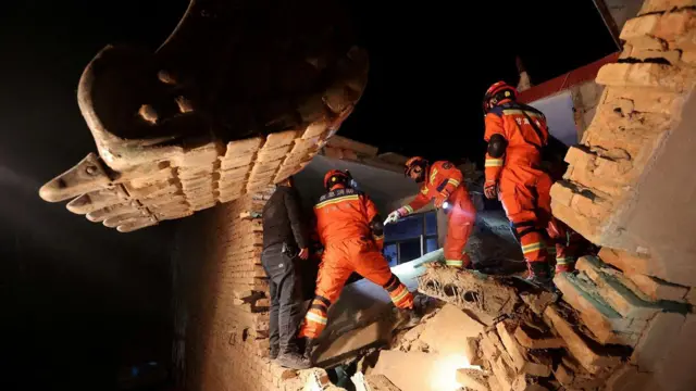 Trabalhadores atuando sobre escombros a noite