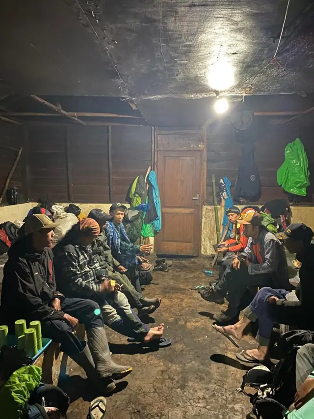 Sekelompok pria sedang berkumpul di dalam ruangan gelap.