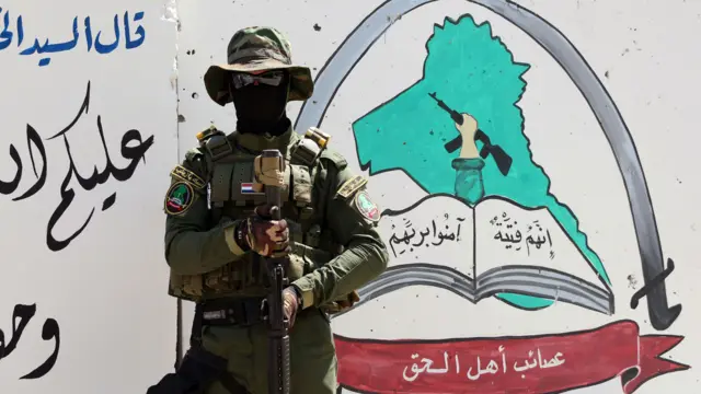 مقاتل من جماعة عصائب أهل الحق الشيعية يقف خارج مقر الميليشيا في 18 مايو/أيار 2015 في مدينة البصرة ذات الأغلبية الشيعية في جنوب العراق.