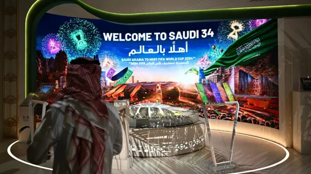 Mężczyzna przechodzi obok stoiska z powitaniem na Mistrzostwa Świata FIFA 2034 w Arabii Saudyjskiej w Ministerstwie Mediów w Rijadzie
