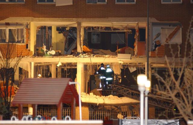 Dois bombeiros em um guindaste trabalham nos destroços do apartamento que jihadistas explodiram