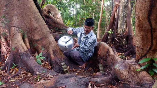 Tetua Pulau Rempang, Muhammad Sani, menyiramkan air di makan tua Lubuk Lanjut, Kampung Pasir Panjang, Rempang, Jumat, 6 September 2024. 