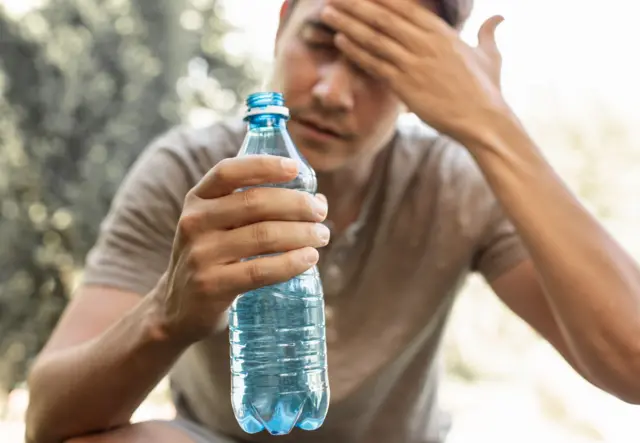 Man drinking water cooling off in extreme summer heat wave. - stock photo