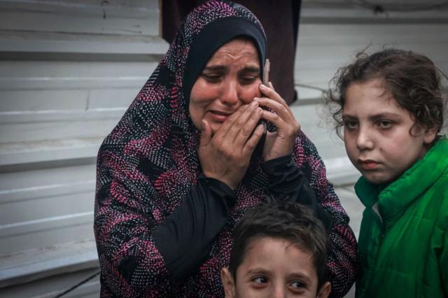 امرأة نازحة تبكي وهي تتصل بأقاربها في مخيم نازحين في رفح