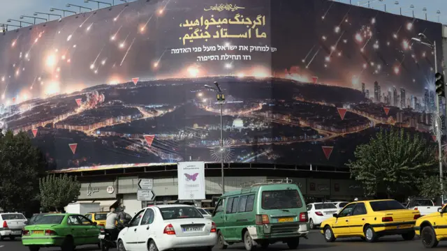 Iranianos passam por um outdoor que retrata o recente ataquejogos para ganhar dinheiro no pix na horamísseis do Irã contra Israel e uma frasejogos para ganhar dinheiro no pix na horapersa que diz: 'Se você quer guerra, nós somos os mestres da guerra'