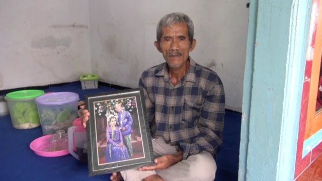 印尼外佣埃拉瓦蒂的父亲手持照片。