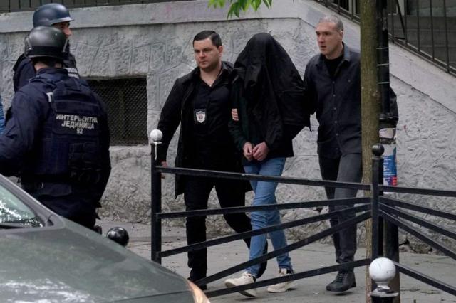A polícia levando um estudanteganhar dinheiro com trader esportivo13 anos algemado (com o rosto coberto)