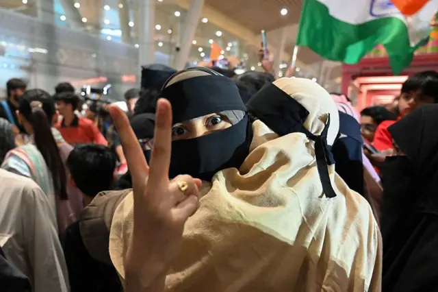 Penumpang Muslim India memberi isyarat saat disambut di bandara Ahmedabad pada Selasa malam (03/03), setelah ia terdampar di Jeddah (Arab Saudi) saat berkunjung untuk sholat khusus di bulan Ramadan. Pemerintah dan maskapai penerbangan berupaya keras memulangkan puluhan ribu pelancong yang terdampar di Timur Tengah.