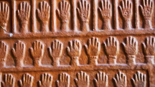 Ukiran tangan-tangan yang mengenang para perempuan yang meninggal karena sati terlihat pada tembok sebuah benteng di Rajasthan, India bagian selatan