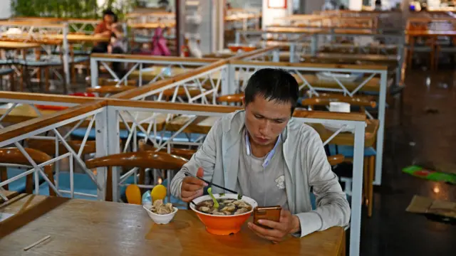 ስልኩን እየተመለከተ የሚመገብ ሰው