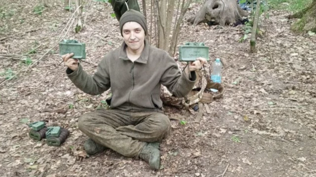 Человек в милитаризированной одежде с минами в руках