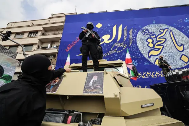 میدان انقلاب، تهران — ۱۱ مارس ۲۰۲۶
نیروهای امنیتی بر روی خودروهای زرهی که با تصاویر علی خامنه‌ای و جانشینش مجتبی خامنه‌ای پوشانده شده‌اند، در جریان مراسم تشییع فرماندهان نظامی کشته‌شده در حملات آمریکا و اسرائیل مستقر شده‌اند.