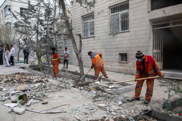 کارگران در حال جست‌وجو در میان آوار ساختمانی هستند که در پی حمله هوایی در یک منطقه تجاری تهران آسیب دیده است؛ ۲۹ مارس ۲۰۲۶