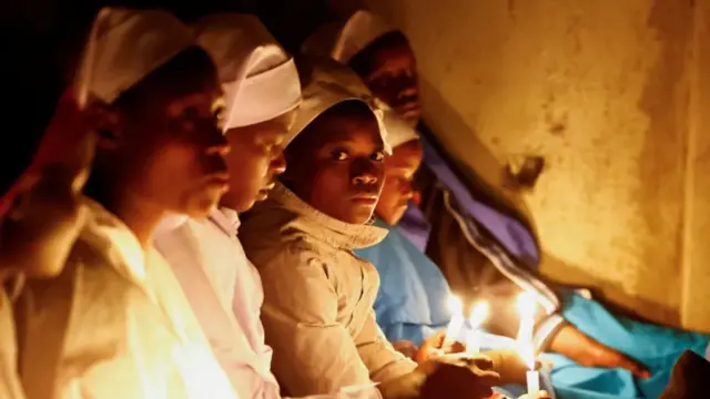 Women hold candle as dem attend Christmas Eve mass for Nairobi, Kenya