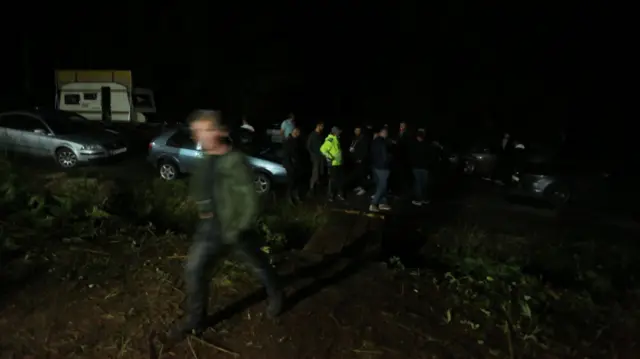 Kolone ljudi noću oko automobila