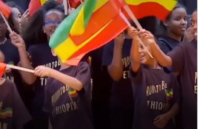 Àwọn tó wo aṣọ dúdú, tí inú wọn ń dùn, wọ́n mú àsíá orílẹ̀ èdè wọn dání