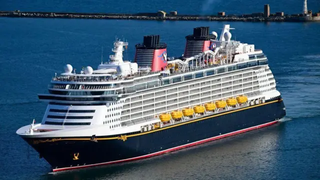 Круїзний лайнер Disney Dream, який видно у воді. На ньому є водна гірка на даху, і він має 14 палуб.