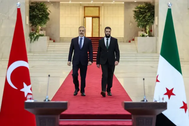 Dışişleri Bakanı Hakan Fidan ve HTŞ lideri Ahmed eş-Şera'nın Şam'da kürsüye yürürken fotoğrafları.