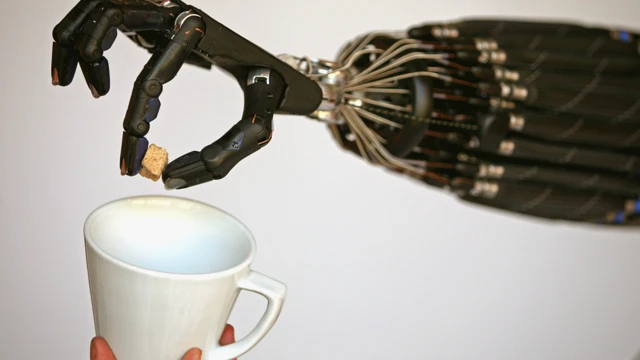 一只灵巧的机械手将一块方糖放入杯子中
