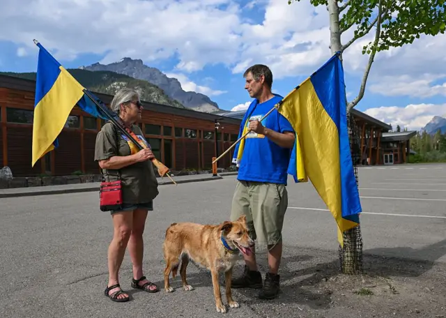 Два человека с украинскими флагами и собакой.