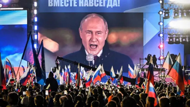 O presidente russo Vladimir Putin aparece em um telão montado na Praça Vermelha enquanto discursa em um comício
