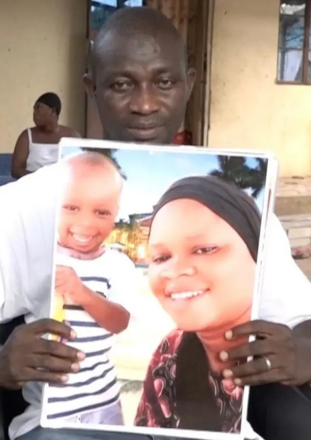 Alieu Kijera tenant la photo de son fils décédé.