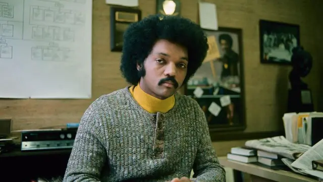 Jesse Jackson in di early part of im career. Im dey sit for im office as e dey look straight at di camera 