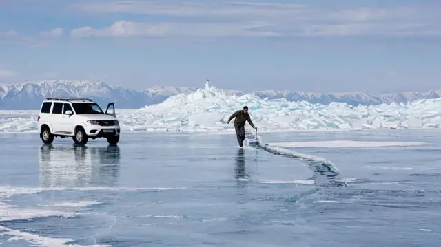 빙하 위에 서 있는 차와 걸어가는 제작진