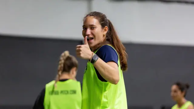 Claudia Rodríguez sonríe a cámara mientras levanta el pulgar, vestida con ropa de fútbol.