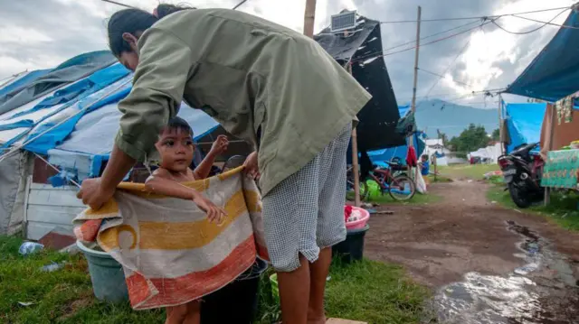 Seorang ibu mengeringkan anaknya dengan handuk setelah di tempat pengungsian Telkom di Palu, Sulawesi Tengah.