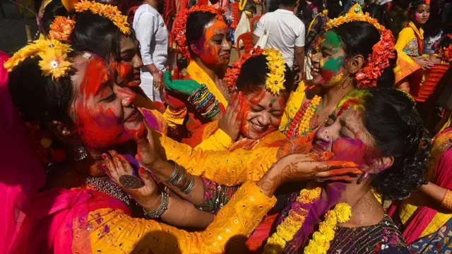 Grupa žena jedna drugoj maže prah u boji po licu i rukama