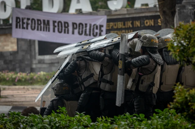 Personel kepolisian berlindung dengan tameng dari lemparan batu pengunjuk rasa di depan Mapolda Jateng, Kota Semarang, Jawa Tengah, Jumat (29/8/2025).