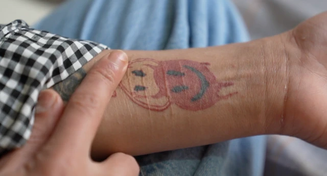 Helma'nın kolundaki kesiklerin üzerinde iki tane yuvarlak gülen şeytan dövmes yer alıyor.
