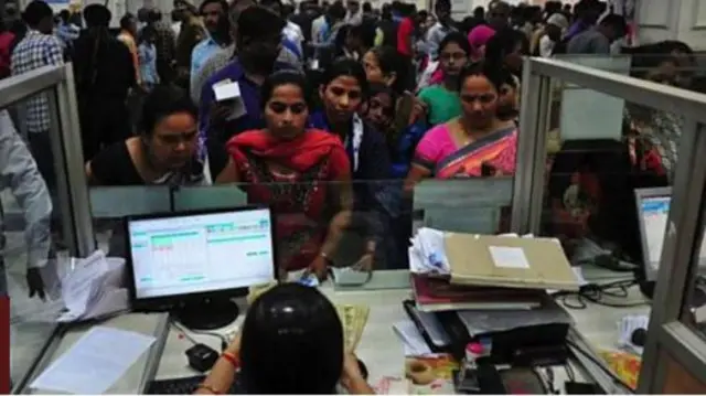 வங்கியில் வரிசையில் நிற்கும் பொது மக்கள்