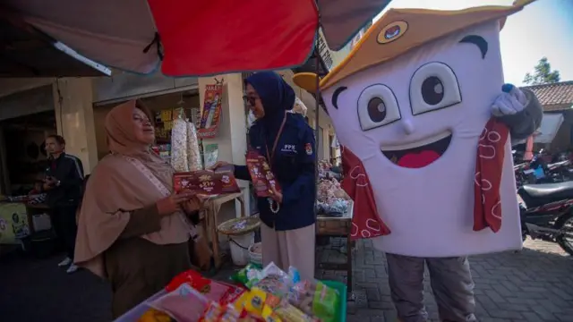 Petugas bersama maskot pemilihan Wali Kota Salatiga membagikan brosur kepada pedagang saat melakukan sosialisasi pelaksanaan Pilkada 2024 di Pasar Cengek, Salatiga, Jawa Tengah, Sabtu (24/8/2024). 