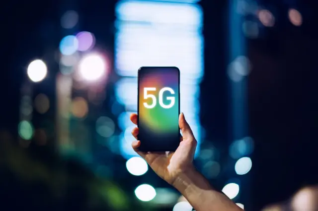 Üzerinde 5G yazılı bir cep telefonu tutan el