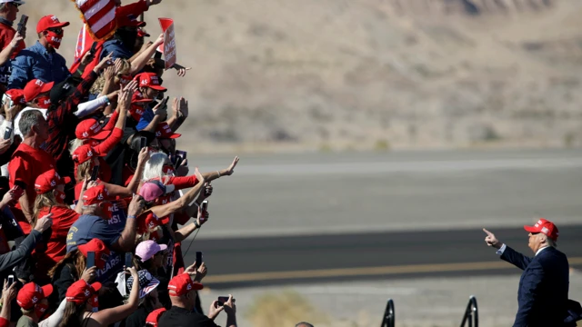 美国总统特朗普在竞选集会结束后向支持者比手势致意