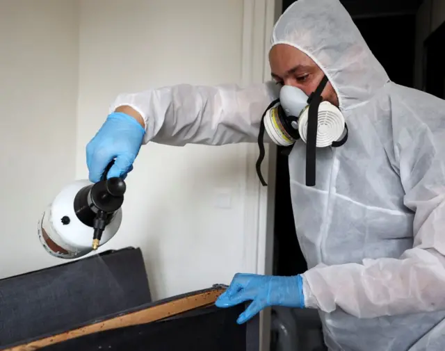 فني المبيدات الحيوية يرش مبيد حشري ضد البق على سرير، بالقرب من باريس