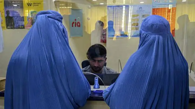 تصویر دو زن چادری پوش در مقابل غرفه صرافی بانک. 