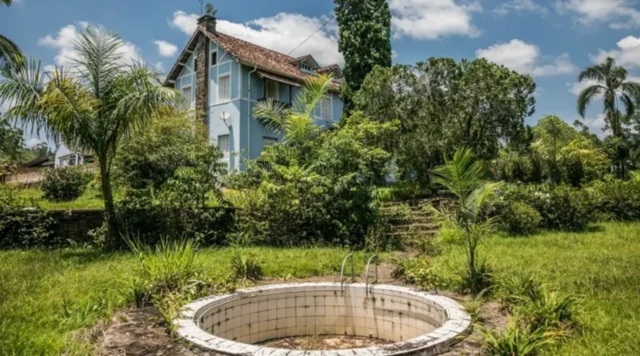 Piscina vazia, com casarão ao fundopaisagem rural