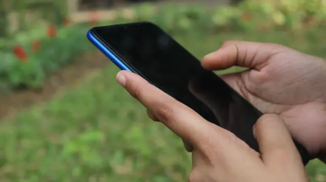 একজনের হাতে একটি মোবাইল ফোন, প্রতীকী 