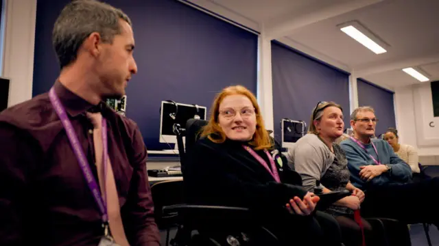 Cinco personas sentadas dentro de una habitación.