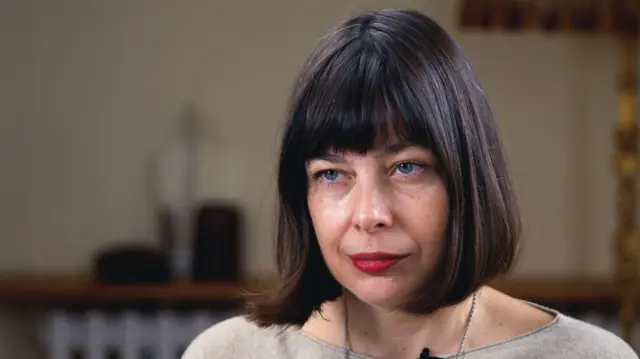 Темноволосая женщина со стрижкой каре смотрит на журналиста