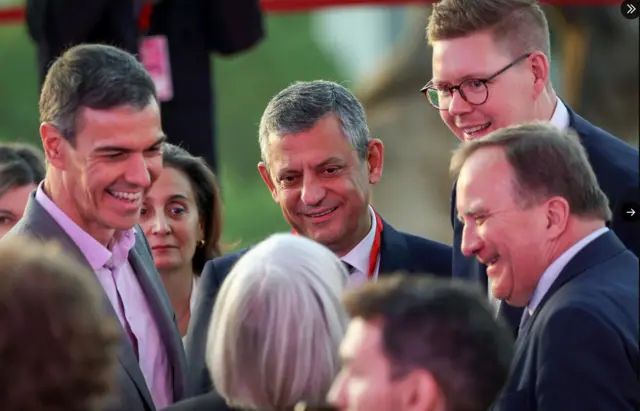 Özgür Özel yanında İspanya başbakanı ile gülerek biribi izliyor.