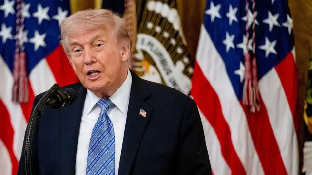 Donald Trump, Washington’daki Beyaz Saray’ın Doğu Odası’nda düzenlenen küçük işletmeler zirvesinde, arkasında Amerikan bayraklarıyla bir kürsüde konuşurken görülüyor.