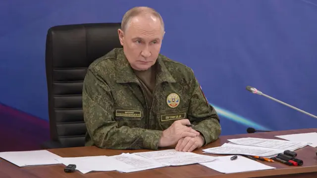 Путін у військові формі сидить за столом