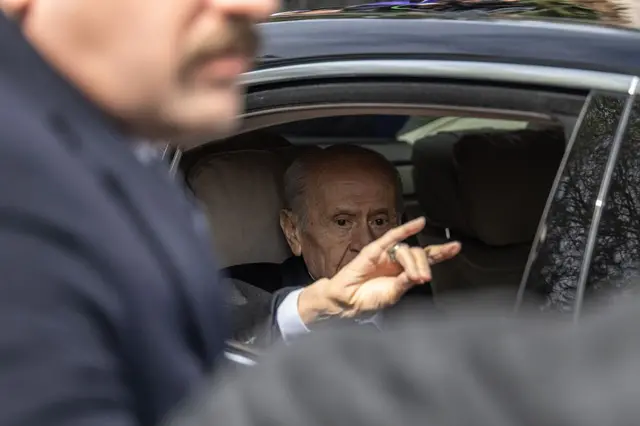 Bahçeli bozkurt işareti yaparak aracından selam verirken. 