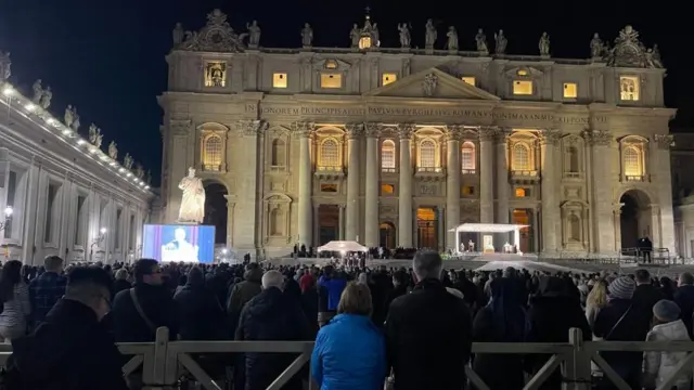 Una multitud de fieles concentrada bajo el cielo nocturno en la plaza de San Pedro de El Vaticano. 